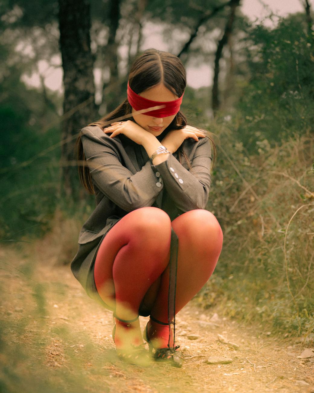 a woman in red tights and a blindfold kneeling on the ground