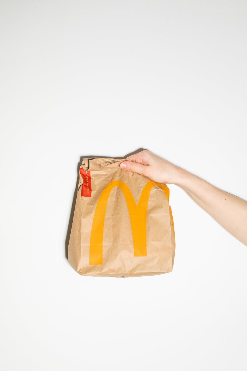 person holding brown and yellow paper bag