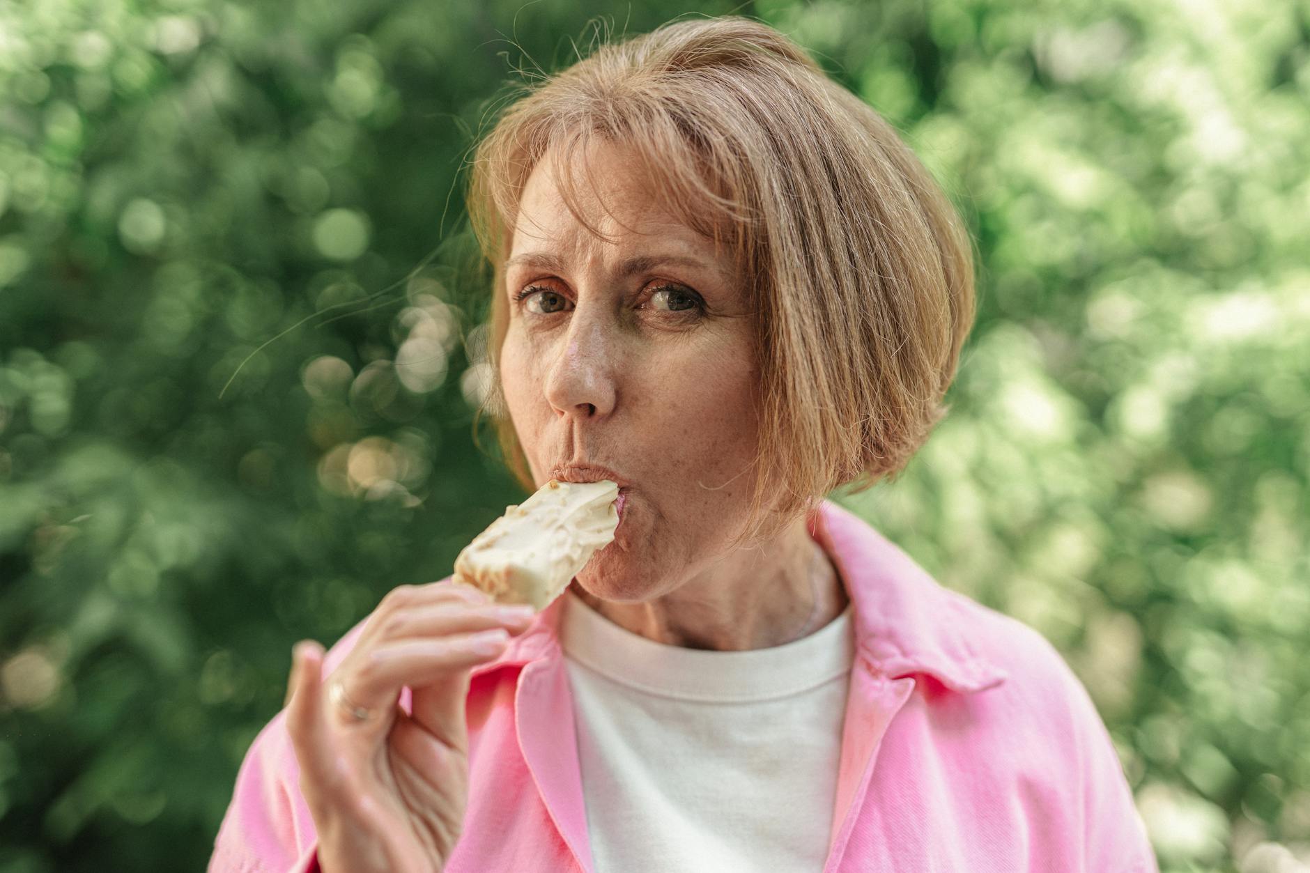 an elderly woman eating an ice cream