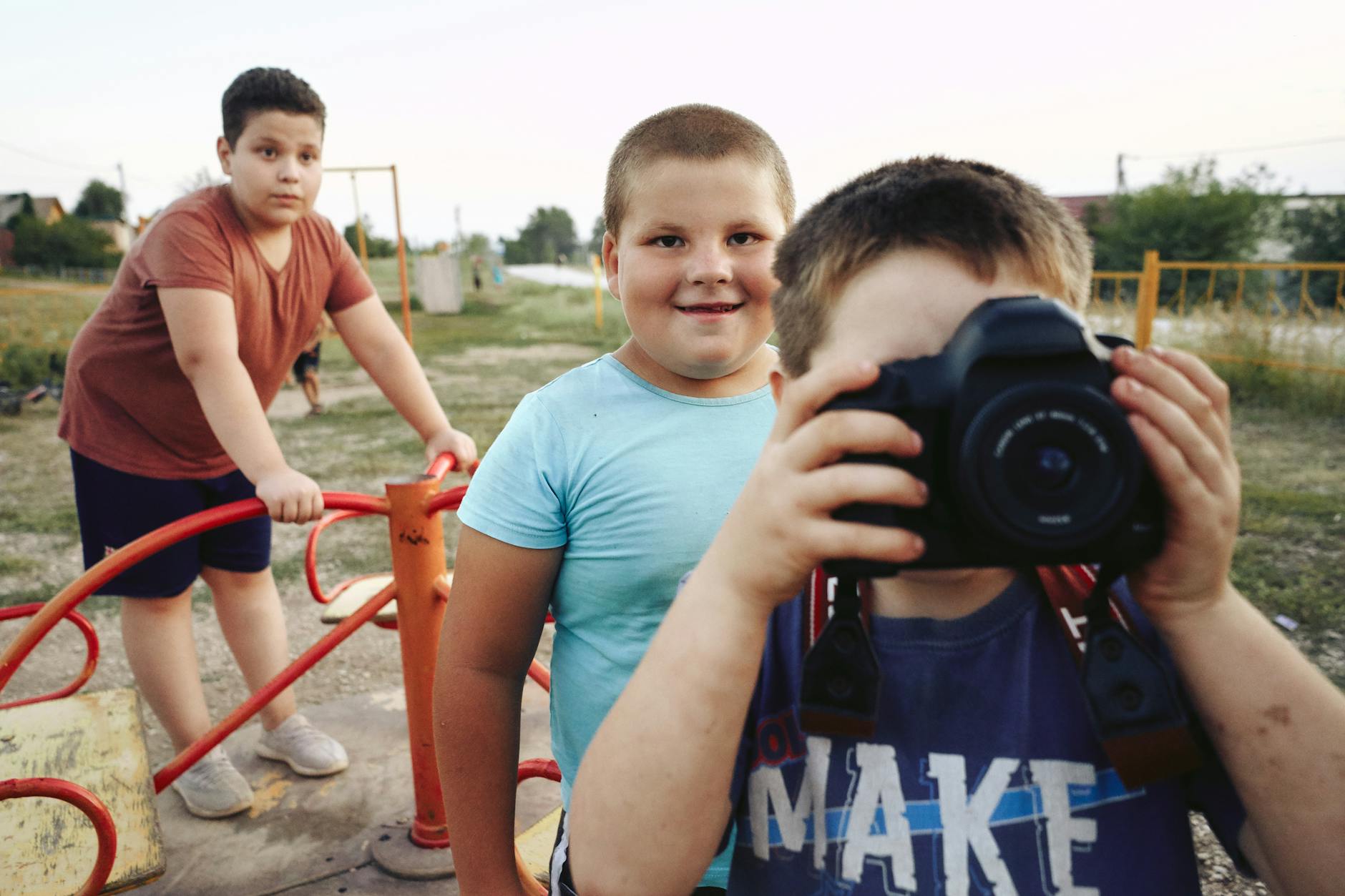 a boy in the playground holding black dslr camera