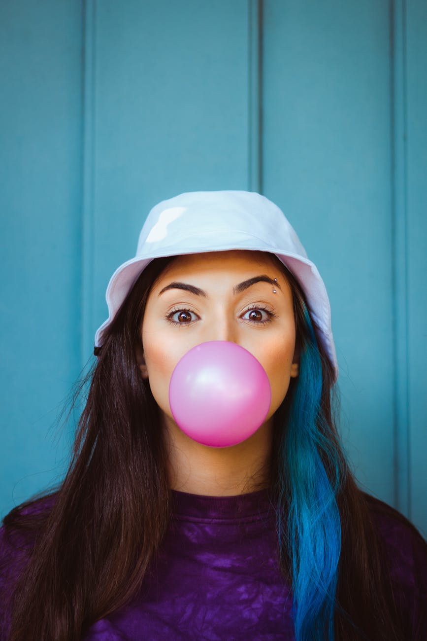 woman blowing a pink bubble gum