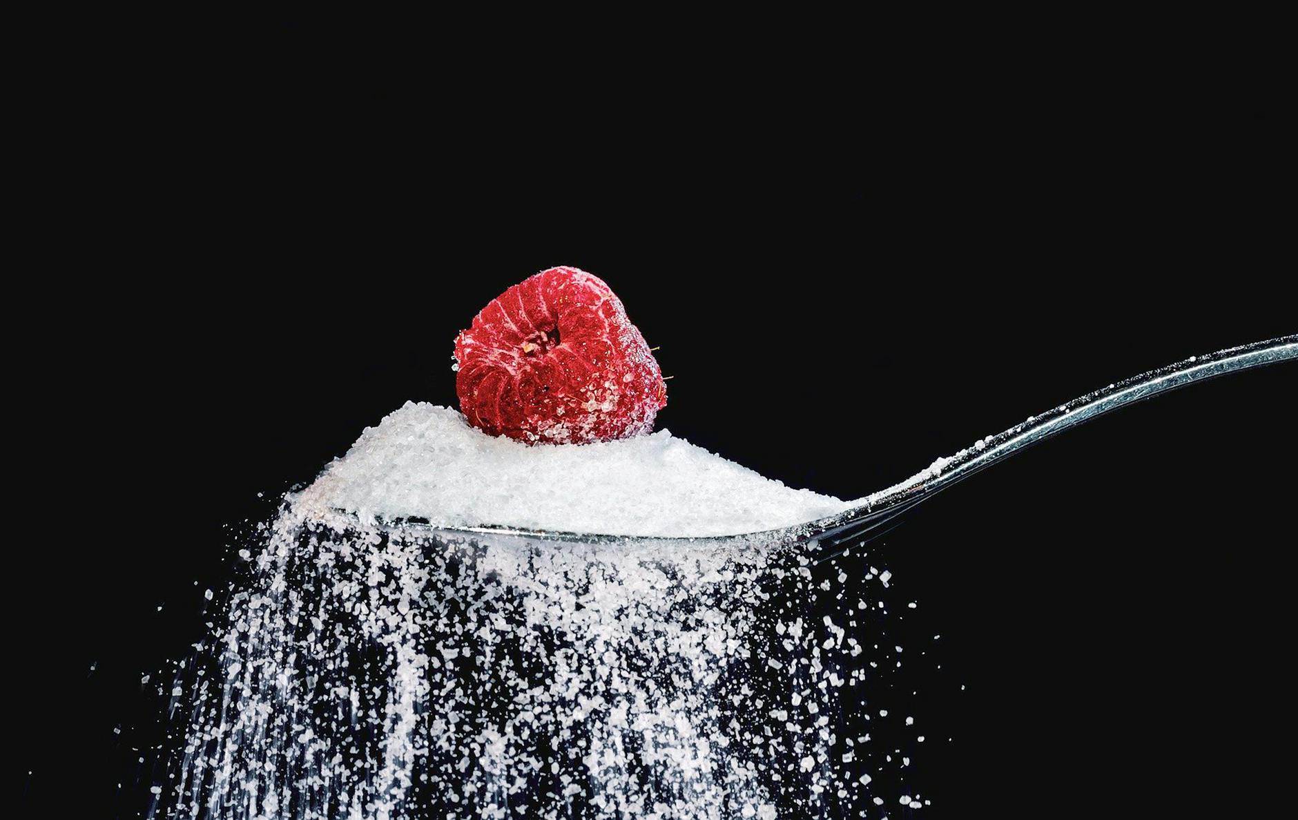 close up photo of a spoon with sugar and raspberry