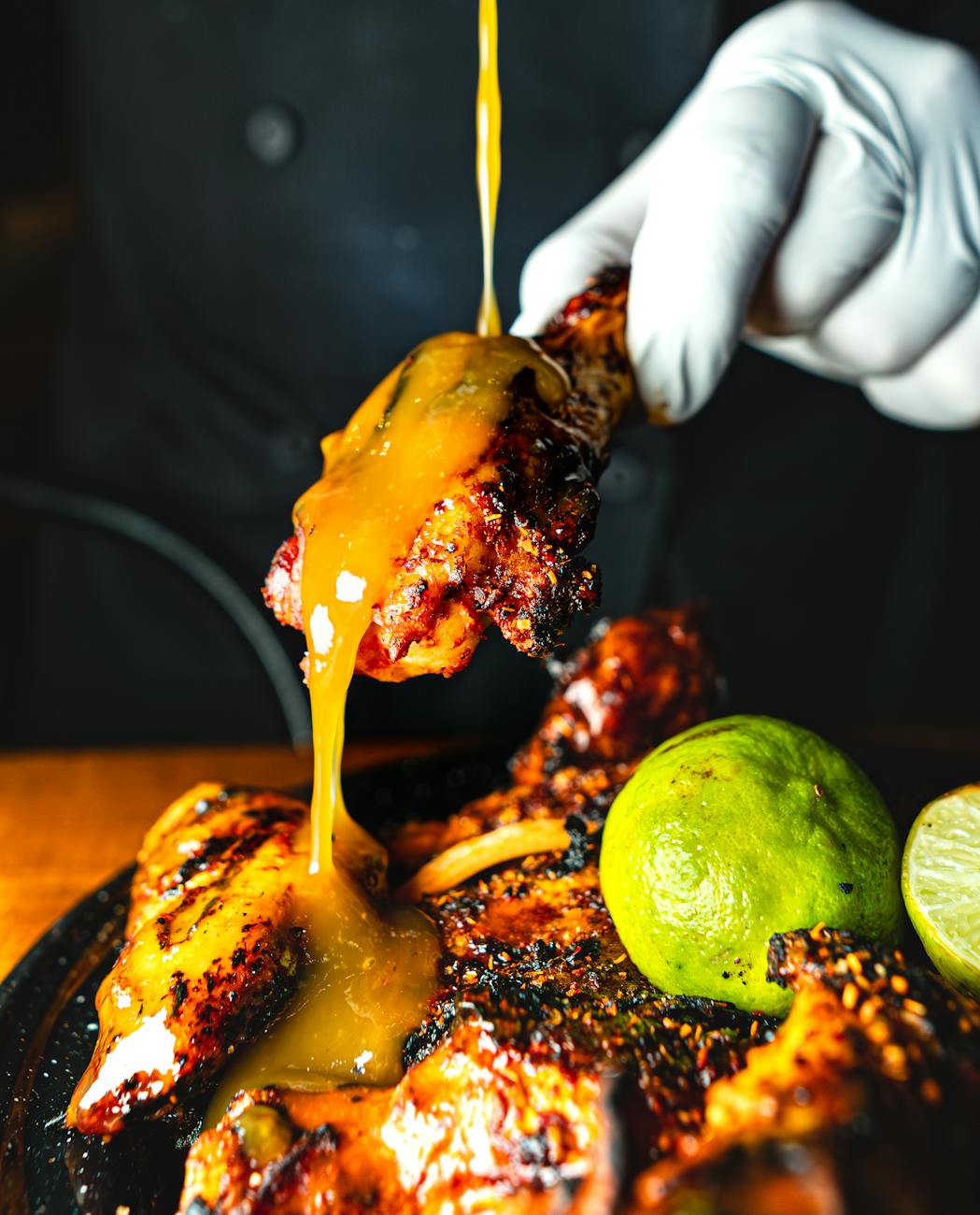 cook pouring sauce on fried chicken