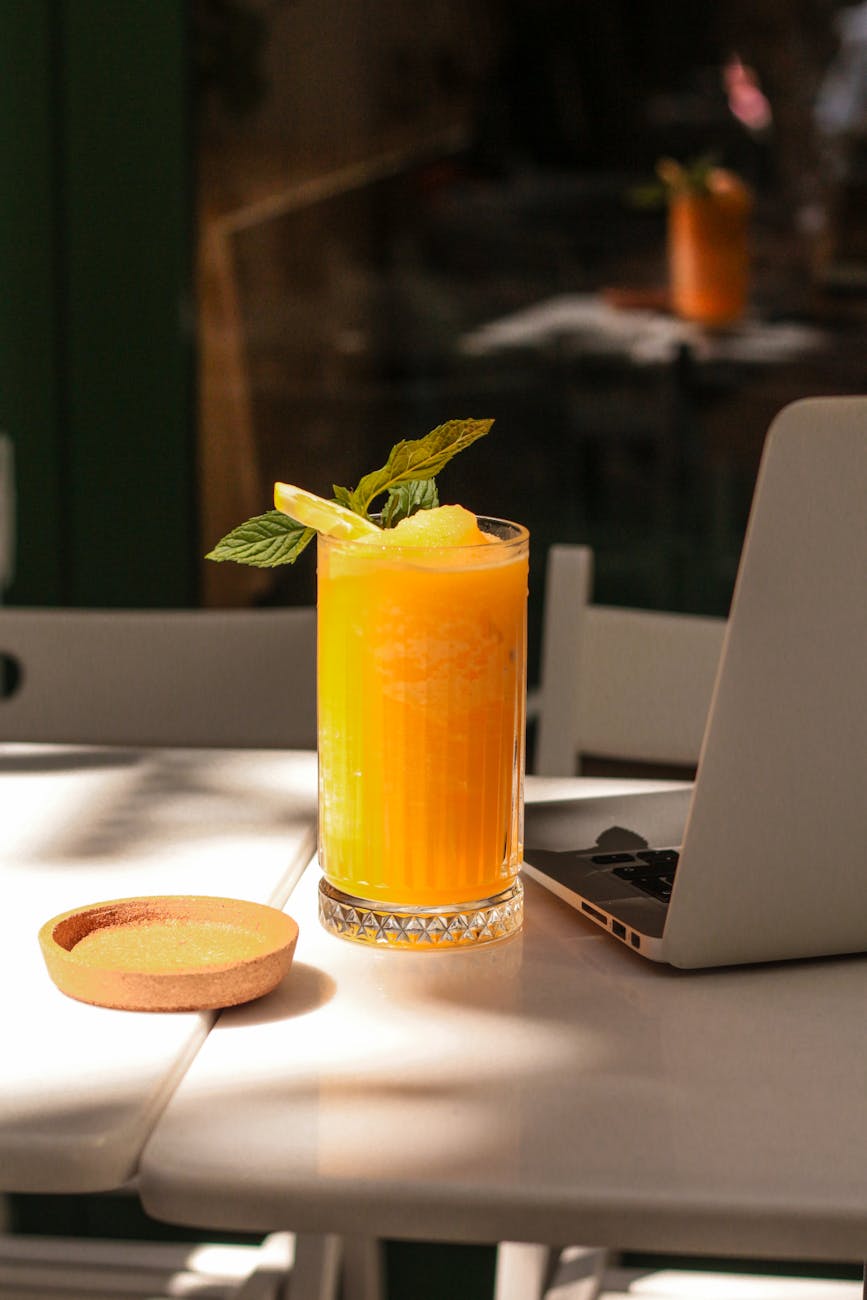 a laptop sits on a table next to a drink