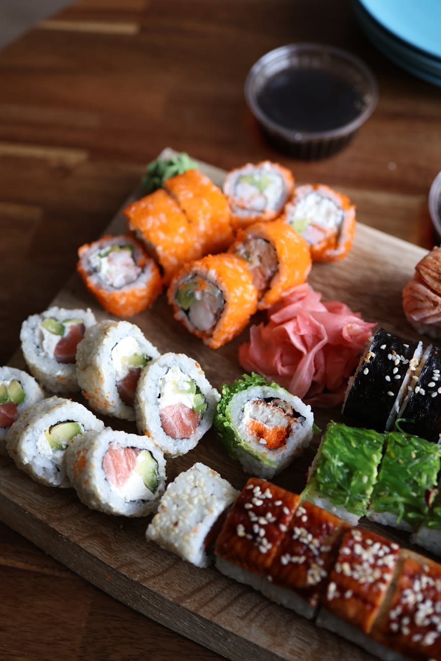 a wooden cutting board with sushi and other food