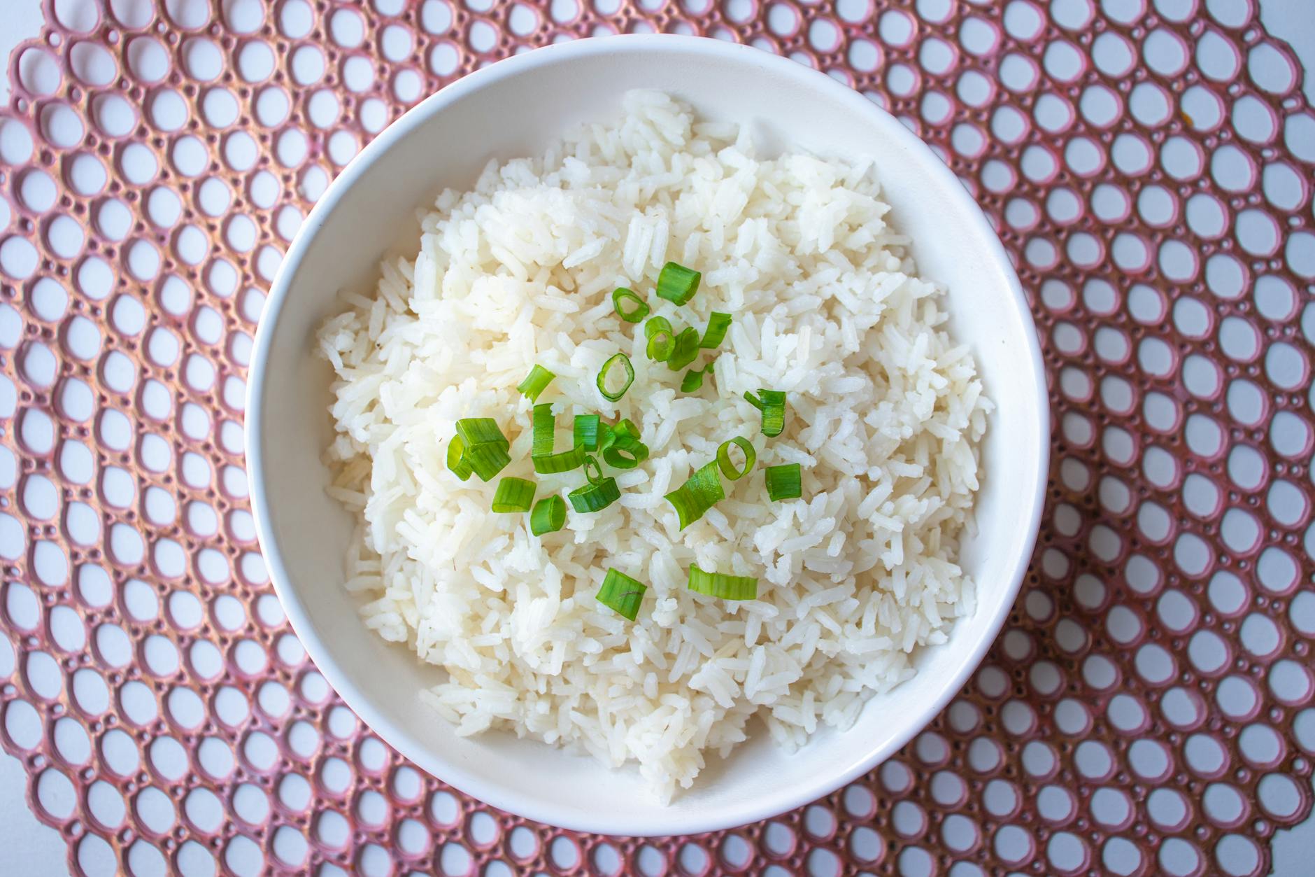 white rice in bowl with green onions top view