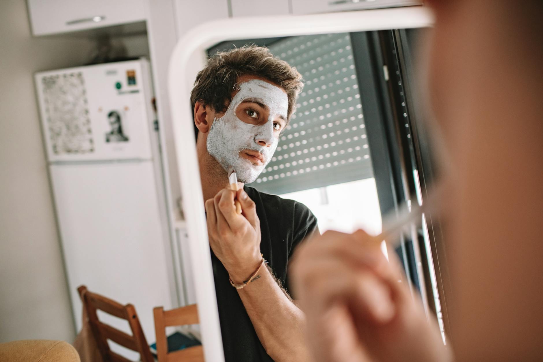 man looking at a mirror putting facial cream