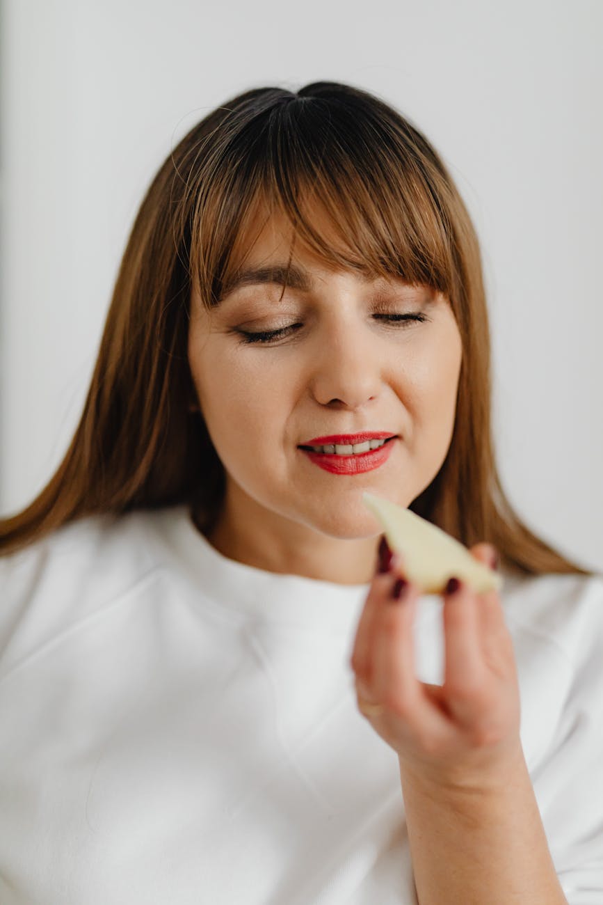 a woman in white holding a slice of cheese