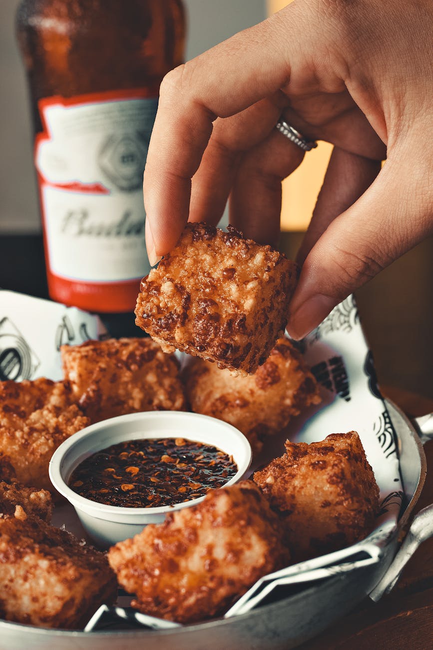 close up of woman about to dip crispy food in sauce