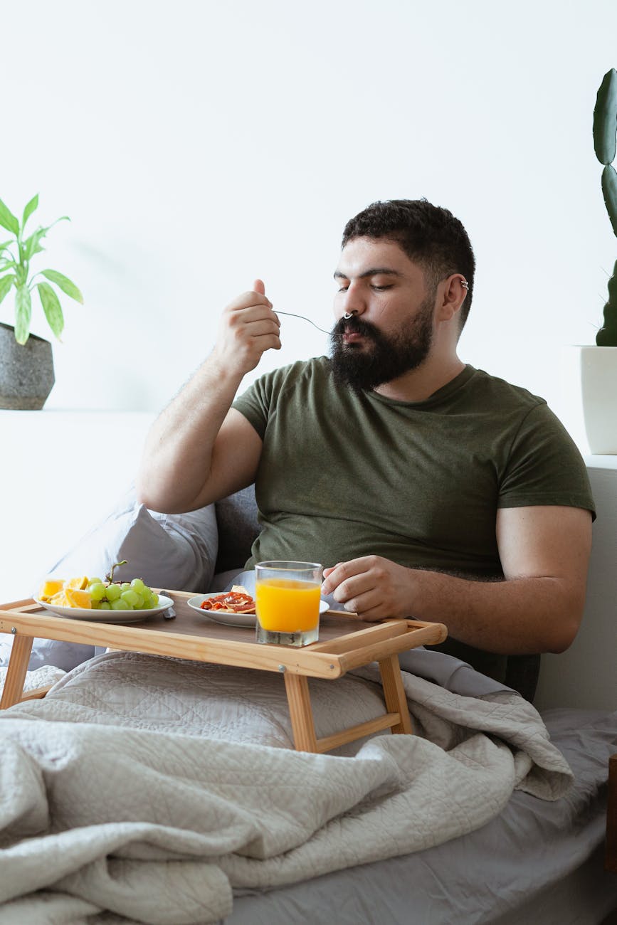 man in green shirt eating on bed