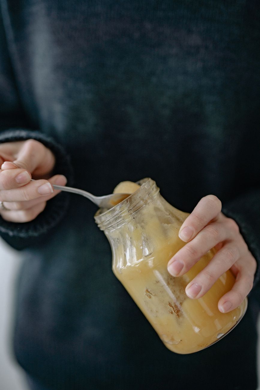 person holding glass jar with honey